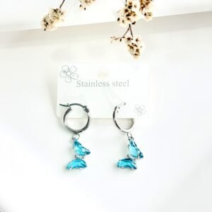 Aros de acero, argolla, dije de mariposa con piedras celestes.