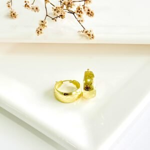 Aros de acero dorado con flores labradas, anchos. 3 cm de diámetro.