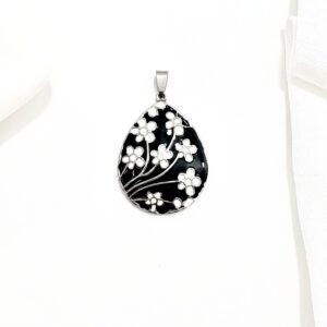 Dije en forma de gota. Flores blancas sobre esmalte negro.