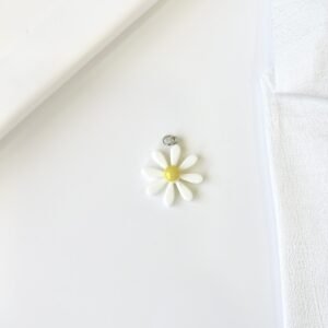 Dije flor blanca, centro amarillo. Fabricado en material plástico.