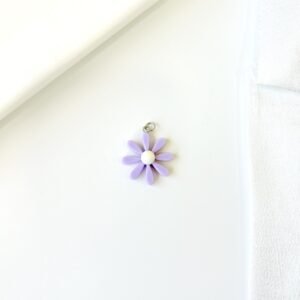 Dije flor lila, centro blanco. Fabricado en material plástico.