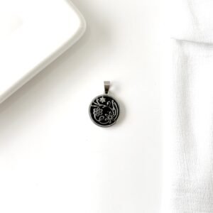 Dije circular, diseño floral. Fondo esmaltado negro.