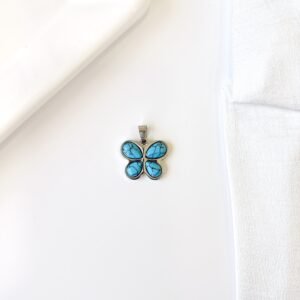 Dije forma de mariposa con piedras de color turquesa.