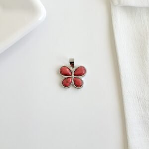 Dije forma de mariposa con piedras de color roja.