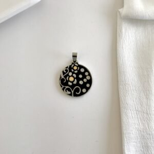 Dije esmaltado negro, flores y puntos dorados.