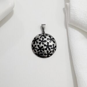 Dije de acero  con flores esmaltadas en negro.