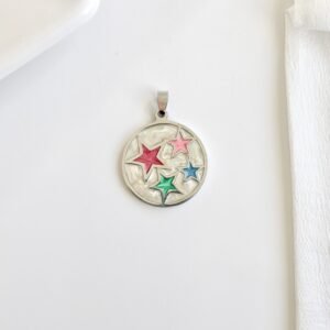 Dije redondo, esmalte blanco, estrellñas de colores.