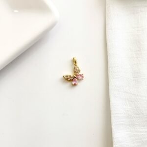 Dije de mariposa dorado con piedras brillantes.