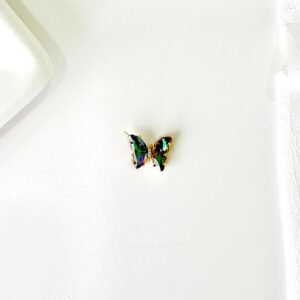 Dije de mariposa dorado con piedras.
