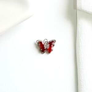 Dije de mariposa con piedras rojas.