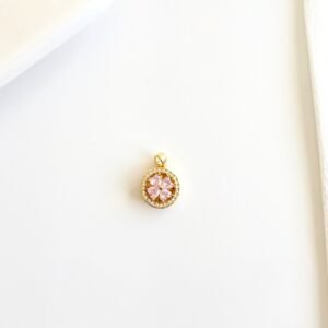 Dije giratorio dorado con piedras rosas y strass.