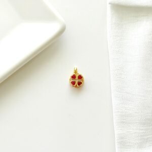 Dije giratorio dorado, trébol con piedras rojas.