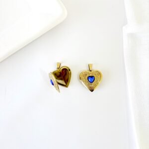 Dije relicario dorado con piedra azul.