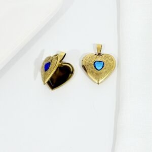 Dije relicario dorado con piedra celeste.