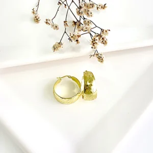 Aros de acero dorado con flores labradas, anchos. 2 cm de diámetro.