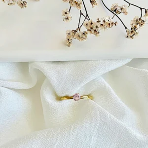 Anillo acero dorado con piedra rosa.